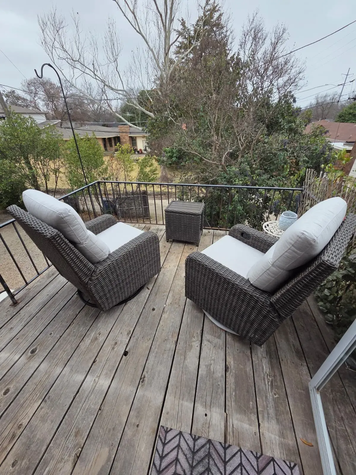 The private deck at The McCosh Apartment with two wicker chairs among the trees
