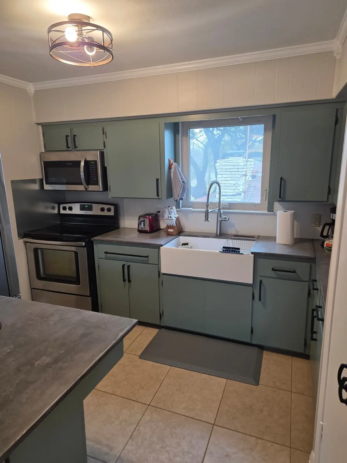 The McCosh Apartment kitchen with green cabinets and a farmhouse sink