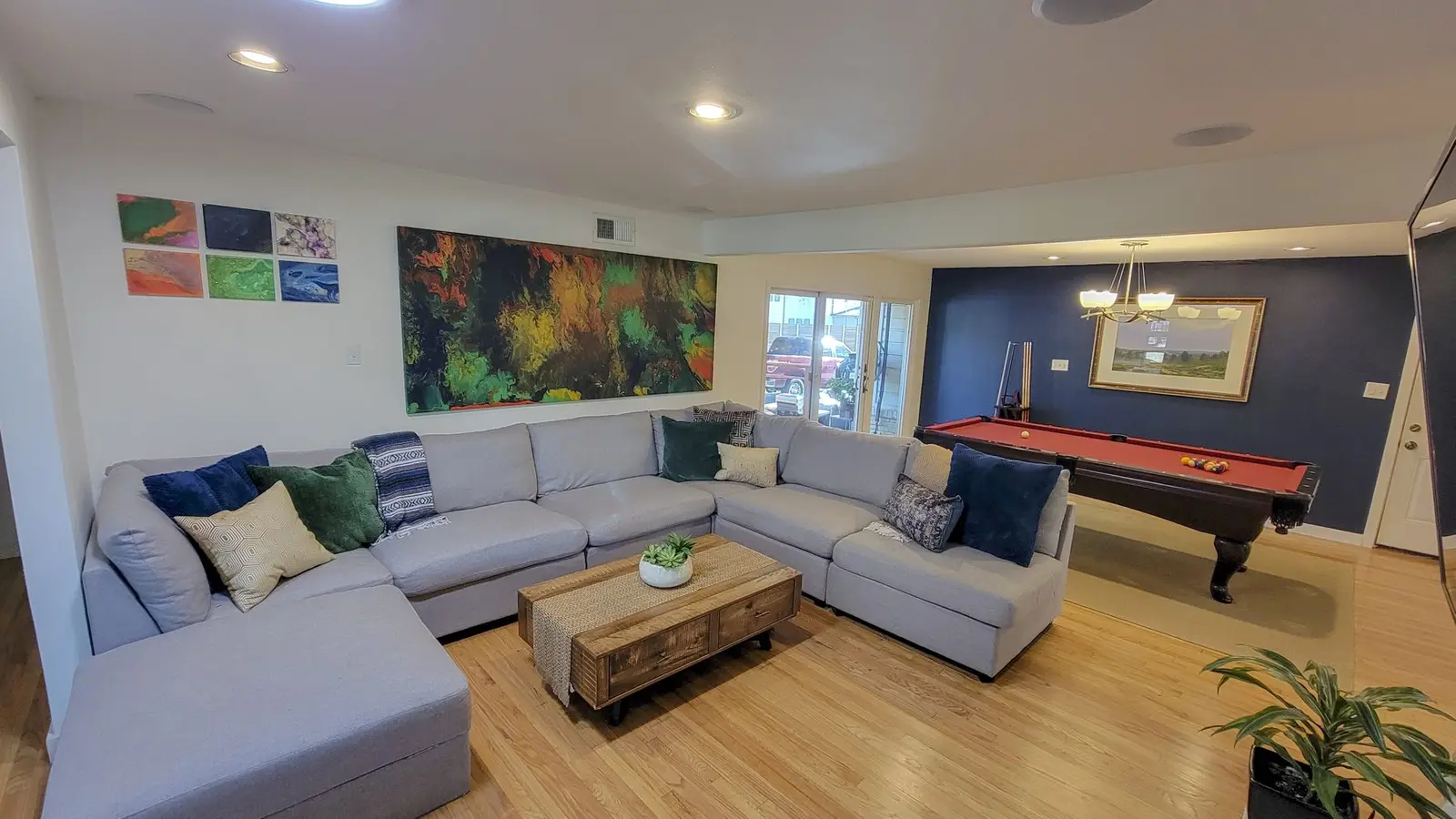 The McCosh House living room with a large sectional and the pool table beyond